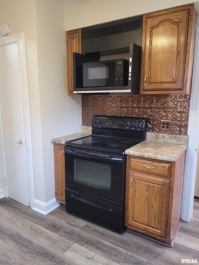 kitchen with black appliances, backsplash, and light hardwood / wood-style flooring