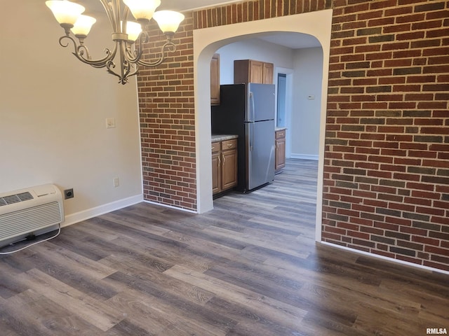 interior space with a chandelier, dark wood-type flooring, and brick wall