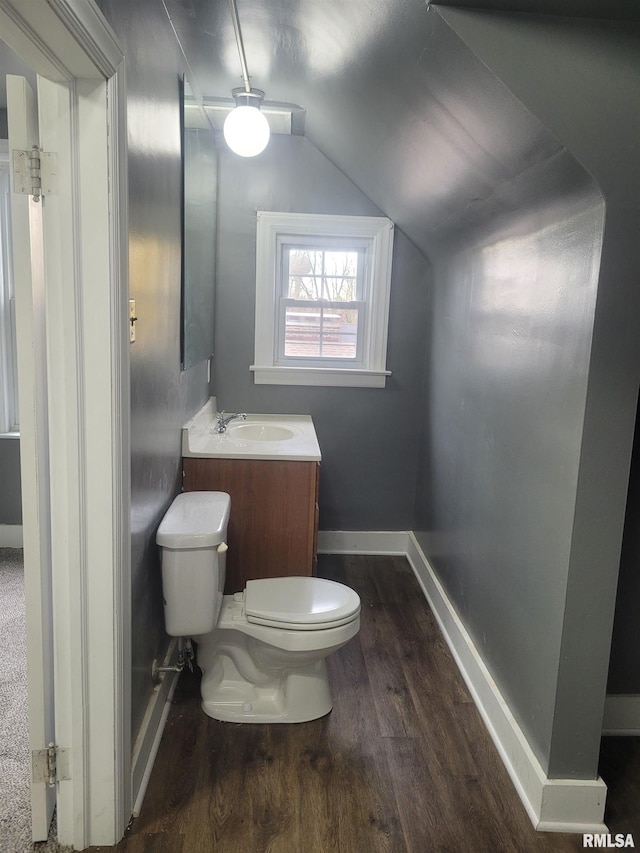 bathroom with toilet, vanity, hardwood / wood-style flooring, and vaulted ceiling