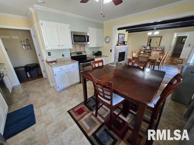 interior space featuring stainless steel appliances, white cabinetry, and crown molding