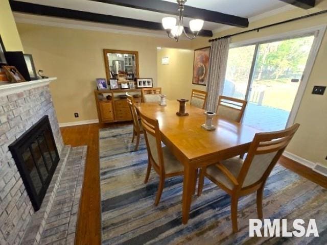 dining space featuring hardwood / wood-style floors, crown molding, a brick fireplace, beamed ceiling, and a notable chandelier