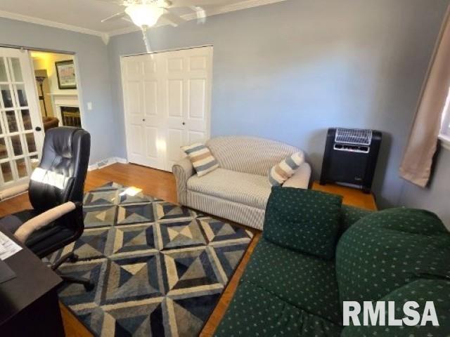 office featuring heating unit, hardwood / wood-style flooring, and ornamental molding