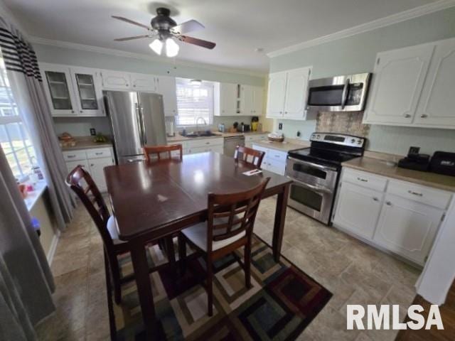 kitchen featuring white cabinets, appliances with stainless steel finishes, crown molding, and sink