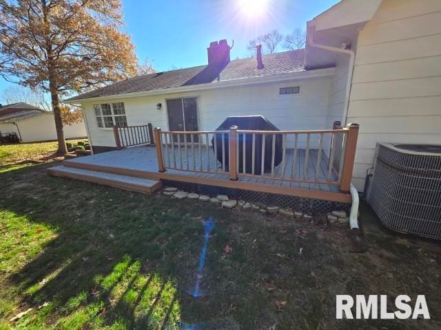 rear view of house featuring central AC unit, a yard, and a wooden deck