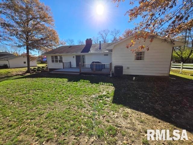 rear view of property featuring a yard, central AC, and a wooden deck