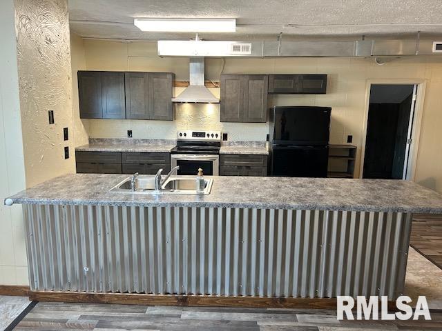 kitchen with black refrigerator, dark hardwood / wood-style floors, stainless steel range with electric stovetop, and wall chimney range hood