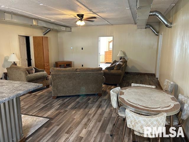 living room featuring ceiling fan and dark wood-type flooring