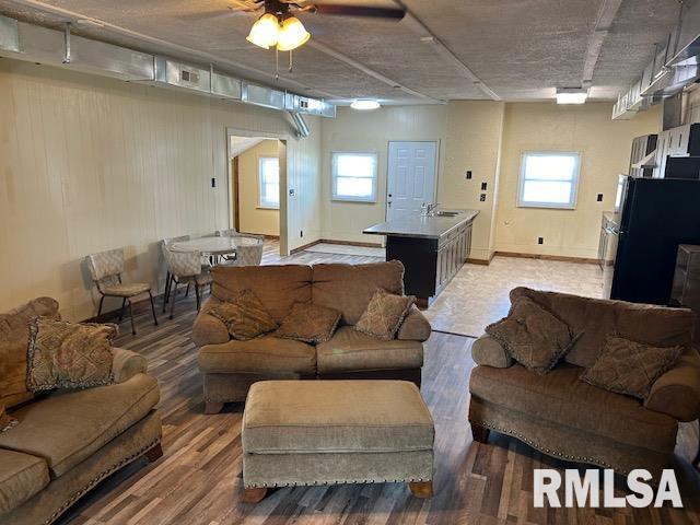 living room with wood-type flooring, a textured ceiling, and ceiling fan