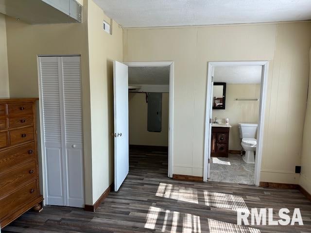 unfurnished bedroom featuring ensuite bathroom, a closet, and dark wood-type flooring