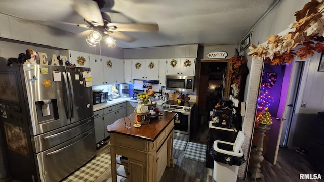 kitchen featuring butcher block counters, dark wood-type flooring, white cabinets, a kitchen island, and appliances with stainless steel finishes