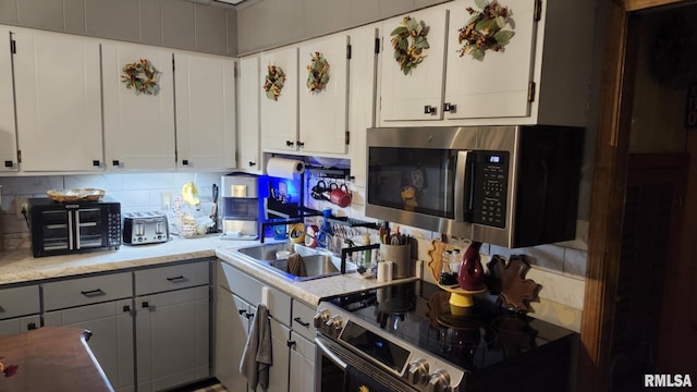 kitchen featuring white cabinets, sink, stainless steel appliances, and tasteful backsplash