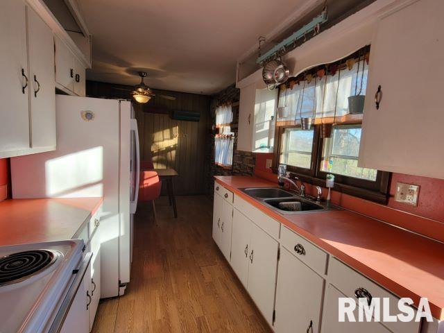 kitchen with light wood-style floors, white cabinetry, a sink, and ceiling fan