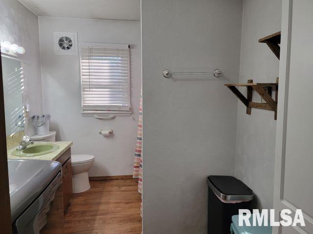 bathroom with vanity, washer / dryer, wood finished floors, and toilet