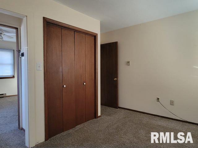 unfurnished bedroom featuring baseboard heating, a closet, and carpet floors