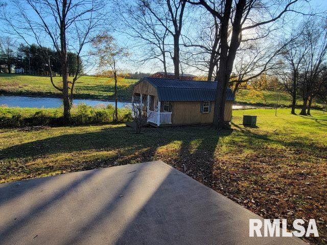 view of yard featuring a storage shed, a patio, and a water view