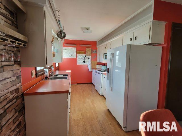 kitchen featuring white appliances, white cabinetry, light wood finished floors, and a sink