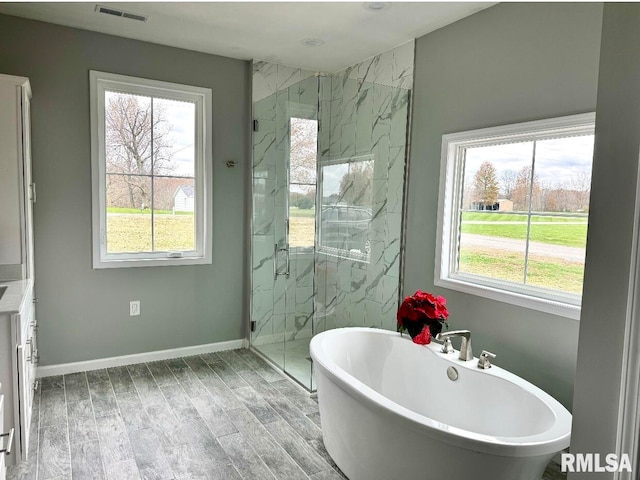 bathroom with a healthy amount of sunlight, wood-type flooring, and independent shower and bath