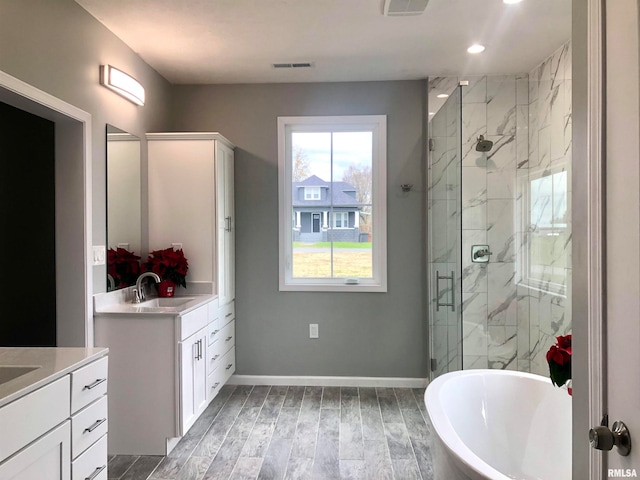 bathroom featuring plus walk in shower, hardwood / wood-style floors, and vanity