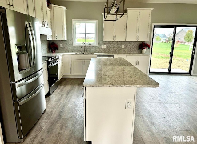 kitchen featuring hardwood / wood-style floors, sink, hanging light fixtures, a kitchen island, and stainless steel appliances