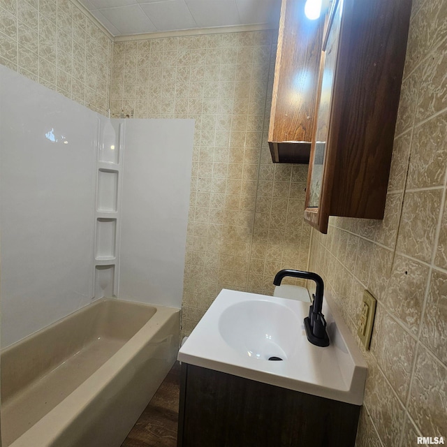 bathroom with washtub / shower combination, vanity, hardwood / wood-style flooring, and tile walls