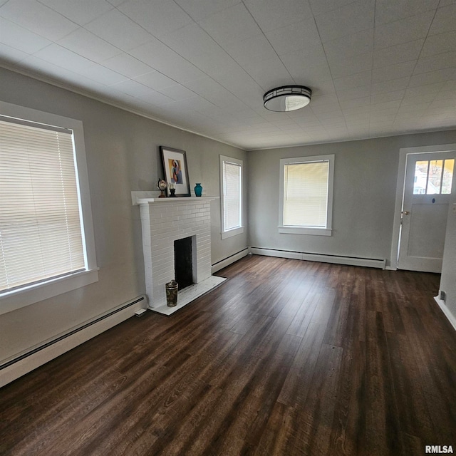 unfurnished living room with baseboard heating, dark wood-type flooring, and a brick fireplace