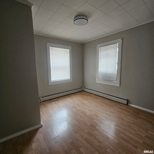 unfurnished room featuring light hardwood / wood-style floors, baseboard heating, and ornamental molding