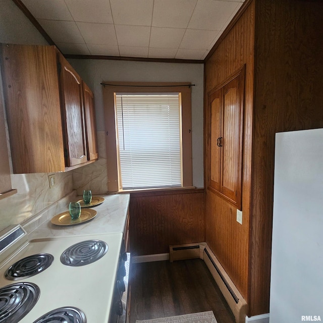 kitchen with baseboard heating, white stove, wooden walls, and dark wood-type flooring