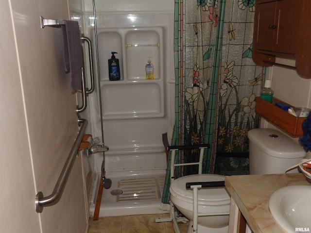 bathroom featuring tile patterned flooring, a tile shower, vanity, and toilet