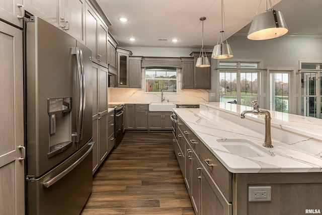 kitchen featuring pendant lighting, dark wood-type flooring, sink, light stone counters, and stainless steel appliances