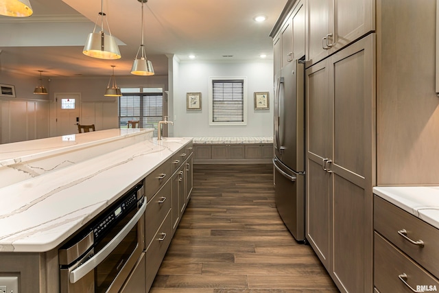 kitchen with dark wood-type flooring, light stone counters, crown molding, pendant lighting, and appliances with stainless steel finishes