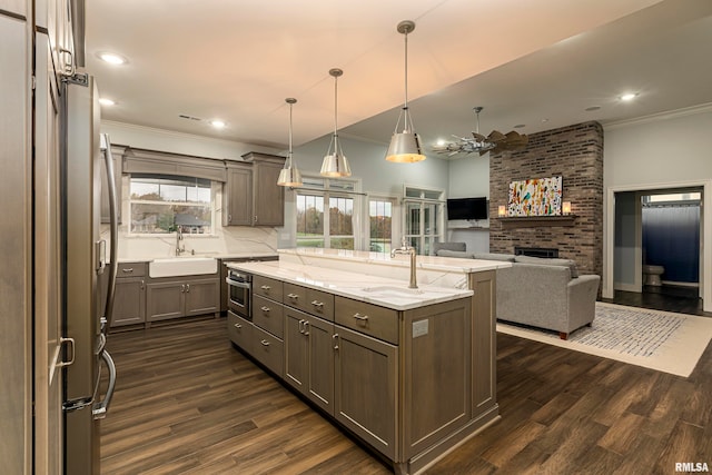 kitchen with a center island, dark hardwood / wood-style floors, light stone counters, and hanging light fixtures