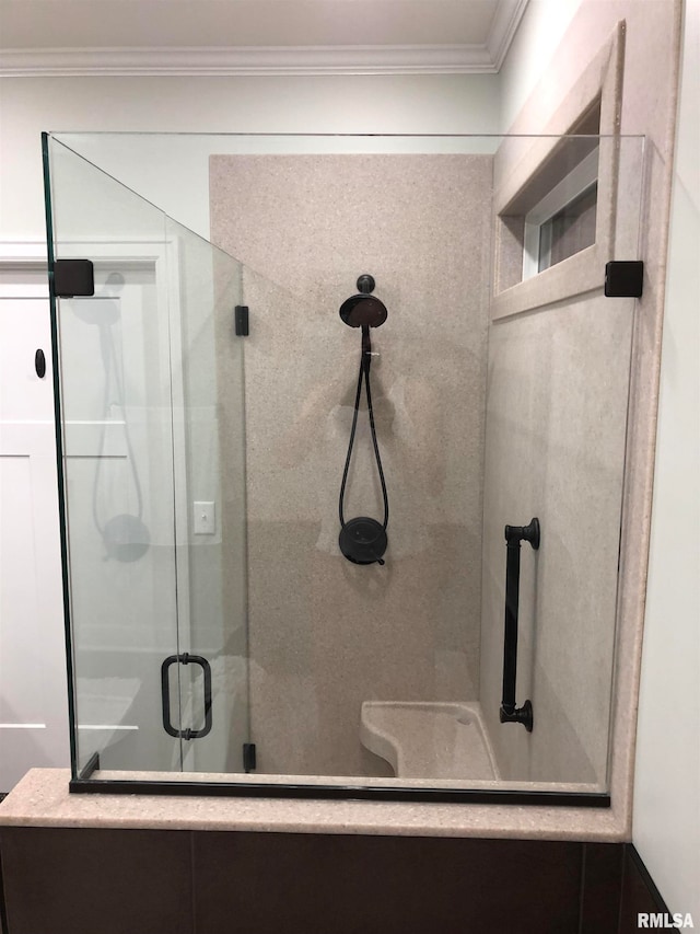 bathroom with a shower with shower door and crown molding