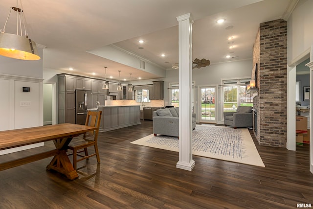 dining area with decorative columns, crown molding, and dark wood-type flooring