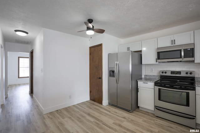 kitchen with stainless steel appliances, visible vents, backsplash, a textured ceiling, and light wood-type flooring