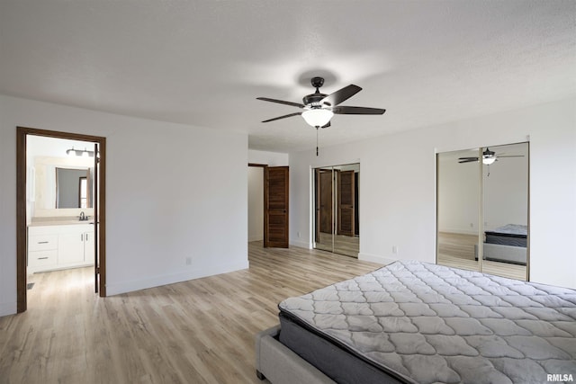 unfurnished bedroom with a textured ceiling, two closets, light wood-style flooring, and baseboards