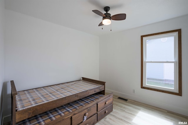 bedroom with light wood-style floors, visible vents, baseboards, and a ceiling fan