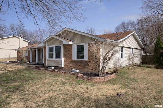 view of front of home featuring a front yard, brick siding, and fence