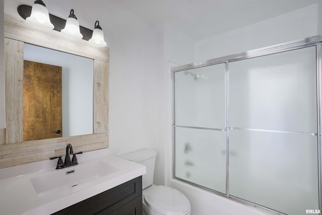 bathroom with toilet, combined bath / shower with glass door, and vanity