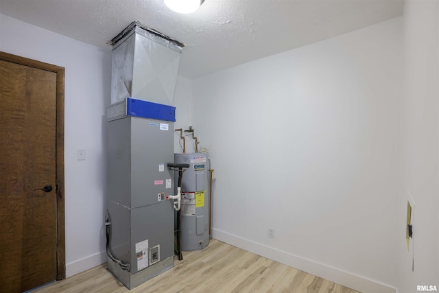 utility room featuring heating unit and electric water heater