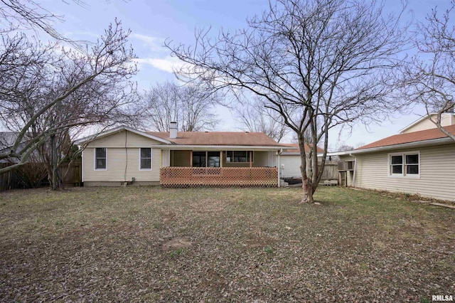 rear view of house with a chimney and fence