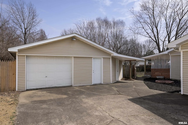 detached garage featuring fence and concrete driveway