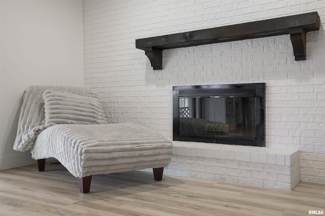 sitting room with a brick fireplace and wood finished floors