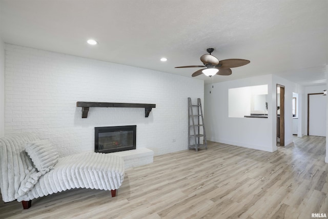 living area with a ceiling fan, recessed lighting, a brick fireplace, and wood finished floors