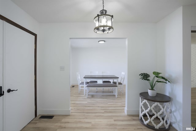 hall with baseboards, an inviting chandelier, and light wood-style floors