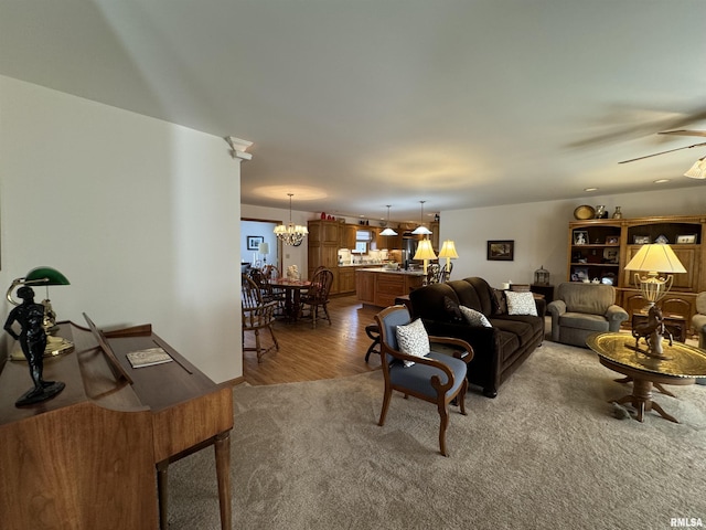 carpeted living room featuring ceiling fan with notable chandelier