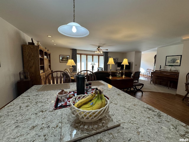 kitchen featuring hardwood / wood-style flooring, light stone counters, and ceiling fan