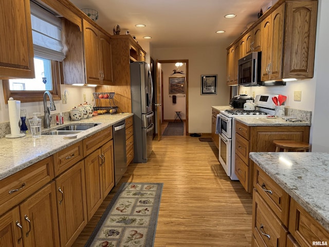 kitchen with light hardwood / wood-style floors, sink, light stone countertops, and stainless steel appliances