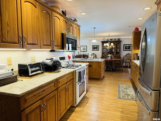 kitchen with pendant lighting, a center island, light hardwood / wood-style flooring, stainless steel appliances, and a chandelier