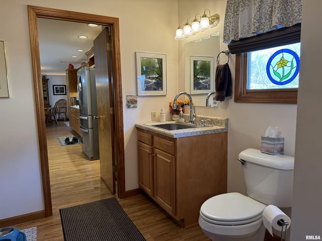 bathroom with wood-type flooring, vanity, and toilet