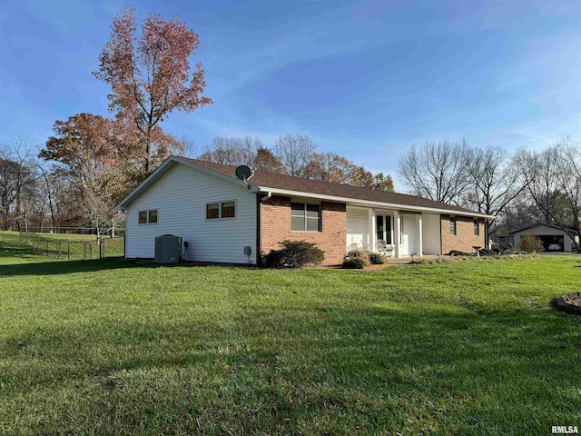 rear view of house featuring cooling unit and a lawn